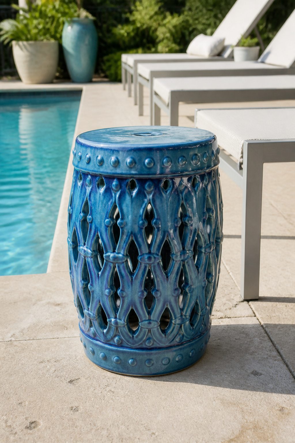 A blue ceramic garden stool positioned next to a lounge chair by the pool.