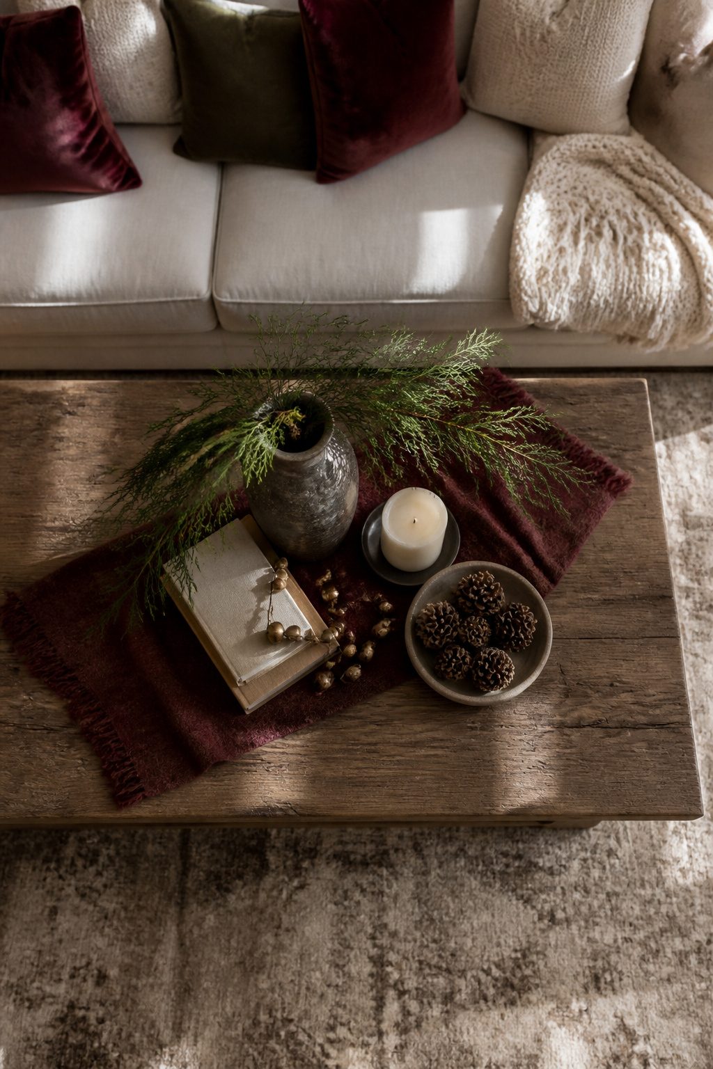 Coffee table with a tray holding a candle, books, and pinecones.