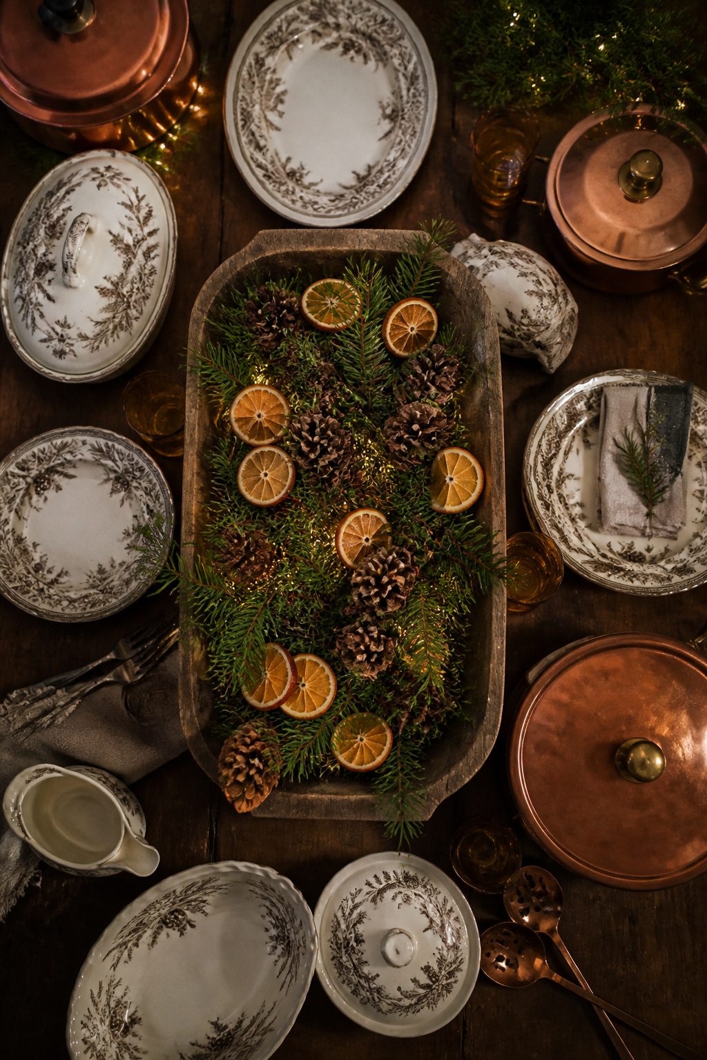 Festive table settings with holiday dishware and copper vessels.